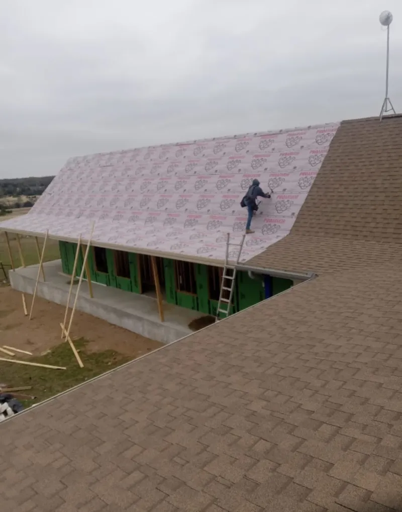 Worker preparing underlayment for a metal roof installation in Siloam Springs